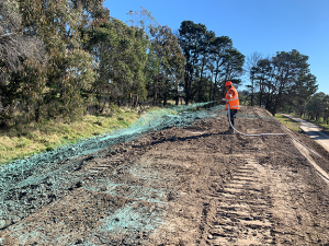 man spraying hydromulch out of hand held hose